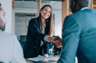 A saleswoman shaking hands with a smiling customer.